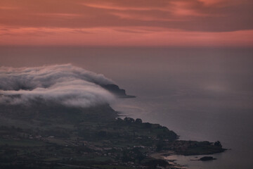 Clouds descend over Playa de la Isla at sunset. Asturias. Spain