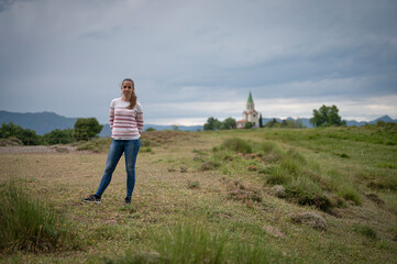 Smiling and cheerful young girl feeling free on the mountain a cloudy day with dramatic sky