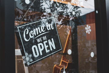 Come in we're open, vintage black retro sign in glass door storefront