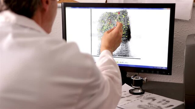 An expert in police science, csi, checks a fingerprint and its matching points on a computer screen