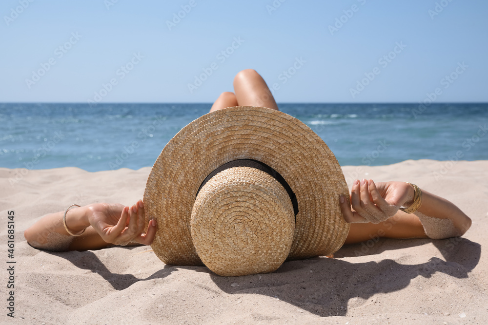 Canvas Prints Woman with straw hat lying on sandy beach near sea