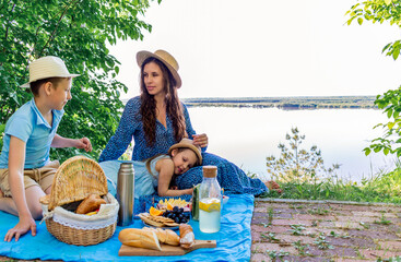 Family outdoor picnic. Mom and the children are eating lunch in nature. Wellness concept.