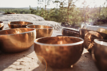 Tibetan bowls stand on the rock in the forest. tools for musical meditation and massage with singing bowls 