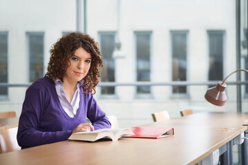 Portrait of female student at desk in library