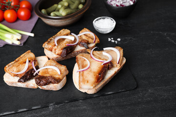 Tasty fried pork lard with bread slices and onion on black table