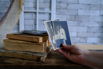 female hand holds vintage photos, retro photography of 1940-1950 on wooden table, old books,...