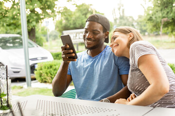 Diverse young couple talking via video call outdoors