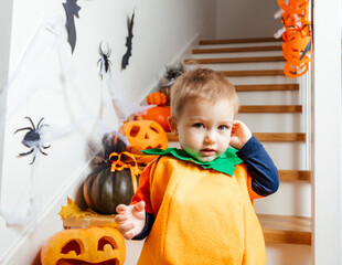 Cute smiling baby dressed as pumpkin looking at camera