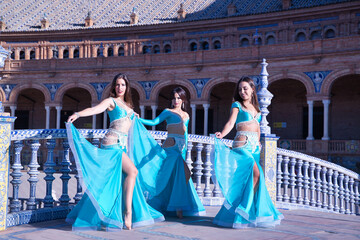 Three middle-aged Hispanic women, showing their turquoise and beaded costumes, for belly dancing....