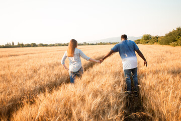 Naklejka na ściany i meble Couple holding hands while walking in field