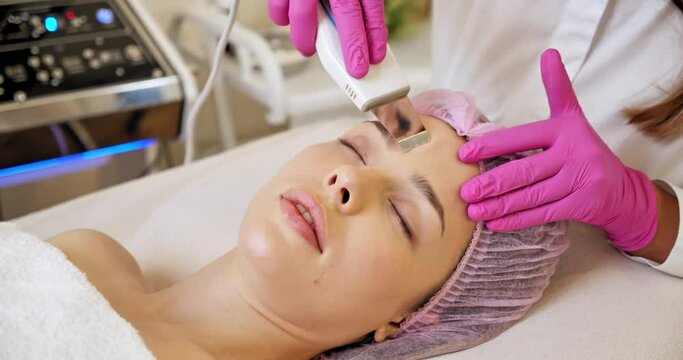Beautiful woman receiving facial microcurrent treatment at spa salon. Beautician using electrical impulses for facial procedures. Woman in spa salon. Woman in a spa salon on cosmetic procedures.