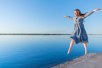 Obraz premium Adult woman in blue dress and straw hat walking near the river. Fortieth people.