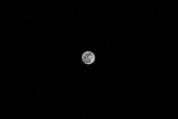 Imagen horizontal de la luna llena sobre un cielo negro.