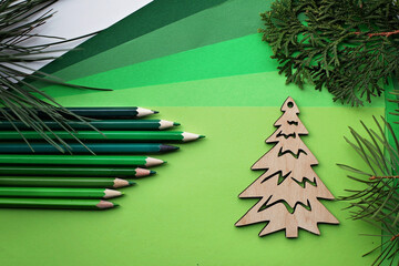 Simple wooden tree and many green color pencils lay on the green color gradation paper background,...