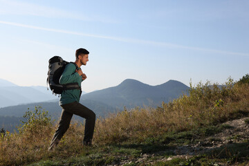 Naklejka na ściany i meble Tourist with backpack in mountains on sunny day. Space for text
