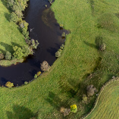 Aerial, drone photography of river, green fields and trees. Photography taken in Sweden in autumn, October. Copy space and place for text.
