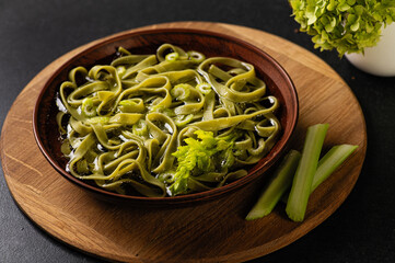 clear broth with homemade noodles, in a ceramic bowl, and dark gray background
