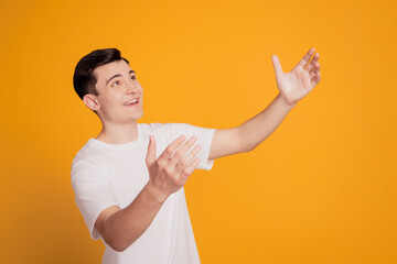 Portrait of funny dreamy inspired guy stretch hand catch hands empty space on yellow background