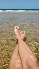 women's feet on the golden sand in the sea, a photo with a view from above