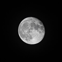 An isolated full moon in the dark black nightsky.