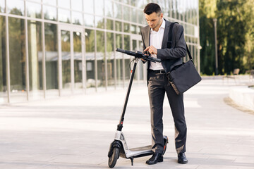Man uses an electric scooter as a modern means of transportation in the city. A male businessman approaches an electric scooter and using mobile phone app. Ecological transportation © uflypro