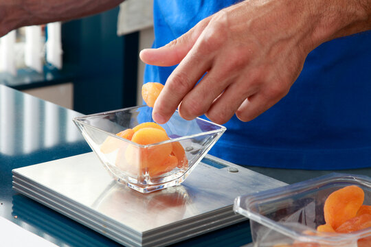 Manos pesando alimento en una  b&aacute;scula. 
Hands weighing food on a scale
