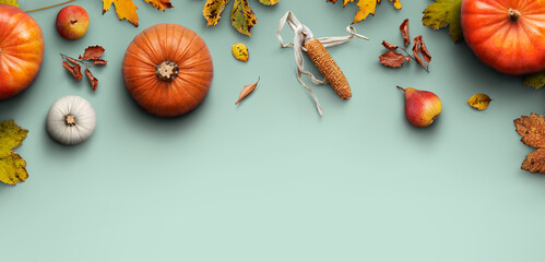 Fototapeta A Thanksgiving autumn harvest background of pumpkins, pears, leaves and corncobs isolated against green worktop. obraz
