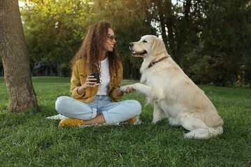 Young African-American woman and her Golden Retriever dog on green grass in park