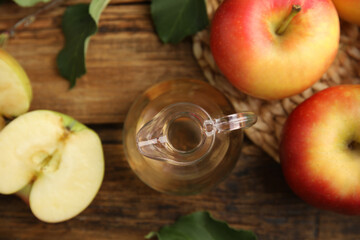 Natural apple vinegar and fresh fruits on wooden table, flat lay