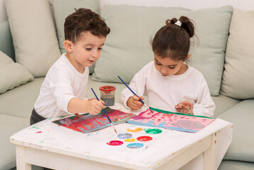 Cute little children is drawing with paints in preschool. Kids making Christmas or Birthday card at home.
