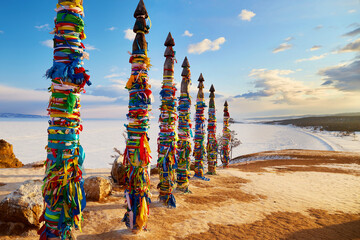 Lake Baikal, Olkhon Island in winter. Wooden ritual pillars with colorful ribbons on cape Burhan or...