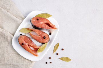 Fresh salmon fish steaks with spices on a white plate. Close-up