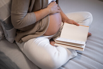 Fototapeta premium Young pregnant woman is reading a book
