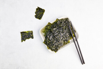 Crispy nori seaweed on bowl with chopsticks. Healthy snack. Traditional Japanese dry seaweed sheets. © Viktoriya