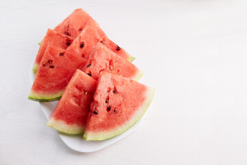 Watermelon slices on a plate on a white wooden background. 