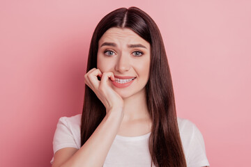 Fototapeta premium Close up portrait of sweet charming girl unhappy sad upset nervous bite fingers teeth isolated pink color background