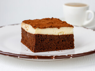 Piece of moist chocolate sponge cake with custurd cream in white plate on table.It called Islak kek or Aglayan Kek in Turkish. Homemade brownie cake with cocoa. Bakery, pastry for tea time in Turkey