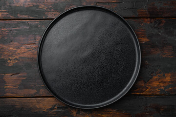 Ceramic empty black plate, on old dark  wooden table background
