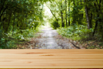 Naklejka na ściany i meble Wood table and blur green tree nature backdrop. Empty wooden table top, surface over blurred garden outdoor