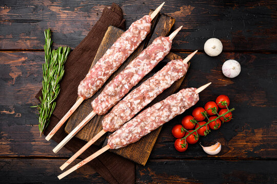 Raw mutton kebab shish skewers, with grill ingredients, on old dark  wooden table background, top view flat lay