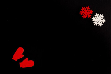 Stylish christmas composition on a black background, wooden figurines of snowflakes and mittens, copy space