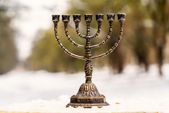 menorah stands in the snow against the background of nature