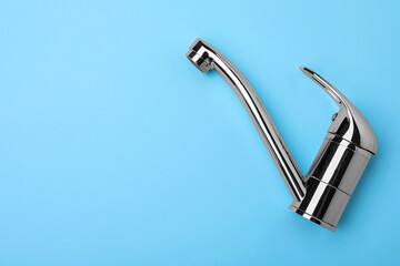 Single handle water tap on light blue background, top view. Space for text