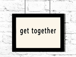 Black frame hanging on white brick wall with inscription get together