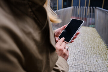 Woman is holding a modern smartphone, sending a text message or using an app on her mobile phone. Internet technology user. Smartphone close-up. Focus on the phone screen