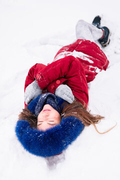 Young happy woman in red coat lying on the snow