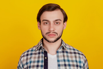Portrait of attractive serious bearded guy wearing checkered shirt isolated over vibrant yellow color background