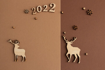 2022, Stylish christmas composition on a brown and beige background, wooden figurines of deer, snowflakes. copy space