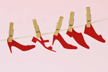 Red paper shoes cut-out hanging on clothesline - Concept of femicide and violence against women - 461714959