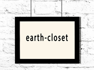 Black frame hanging on white brick wall with inscription earth-closet © iushakovsky